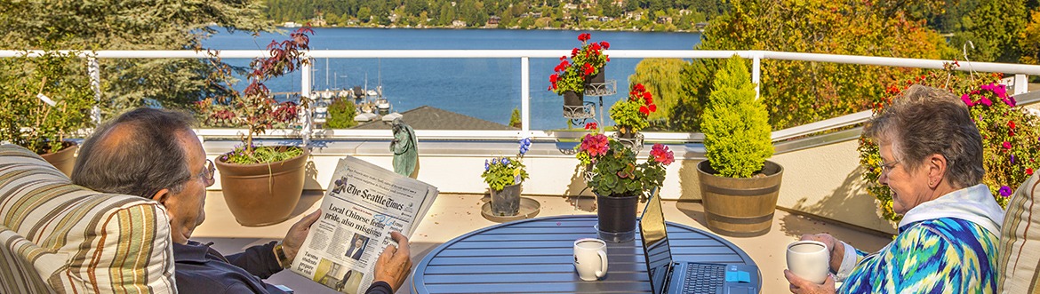 Residents sitting outside on deck at community reading the newspaper