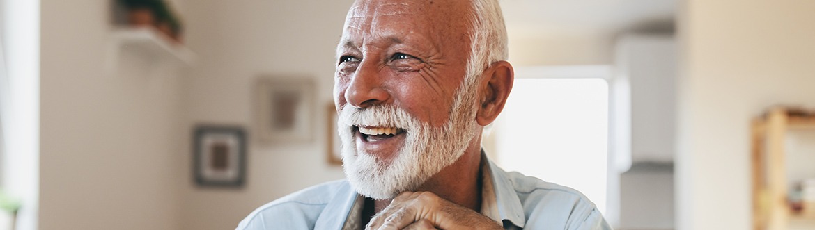 Senior man leaning over cane smiling